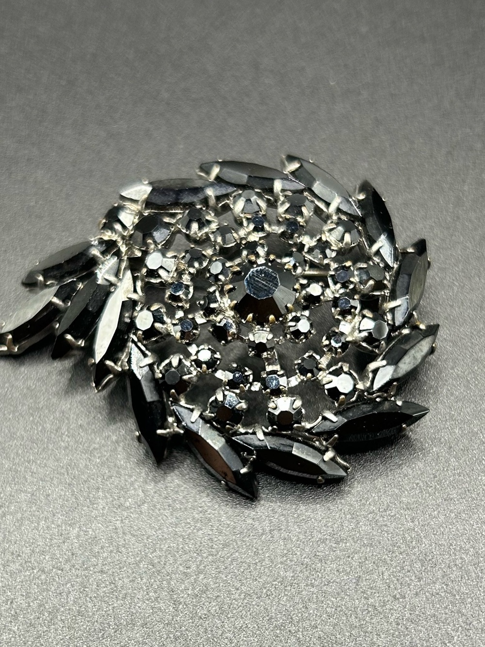 Vintage rhinestone brooch featuring a swirling cluster of dark faceted